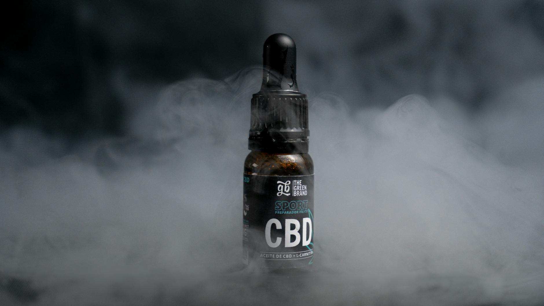 CBD oil bottle enveloped in smoke against a dark backdrop, highlighting the product's mystique.