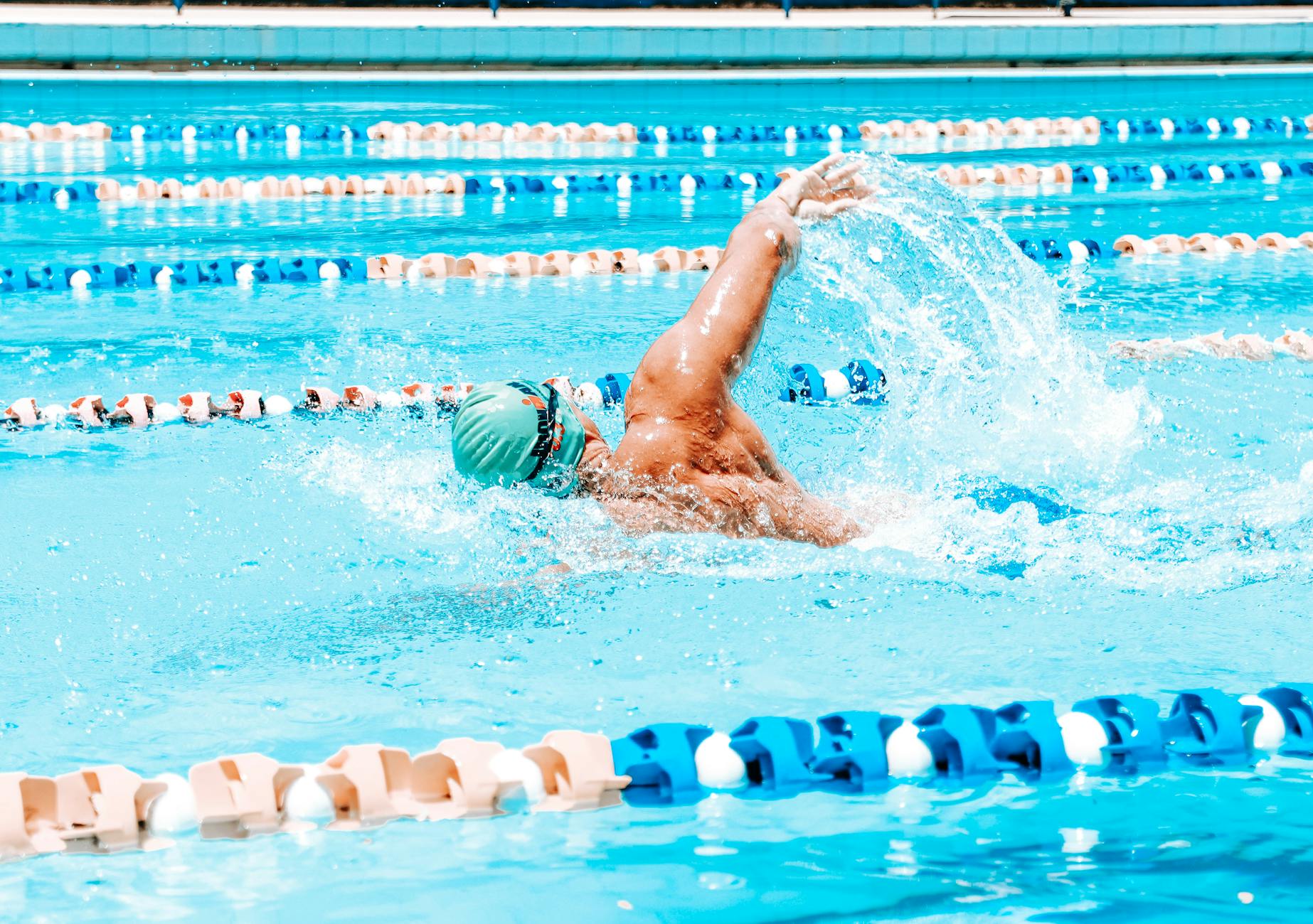 Energetic swimmer performing a stroke in a bright outdoor pool under sunlight in Maceió, Brazil.