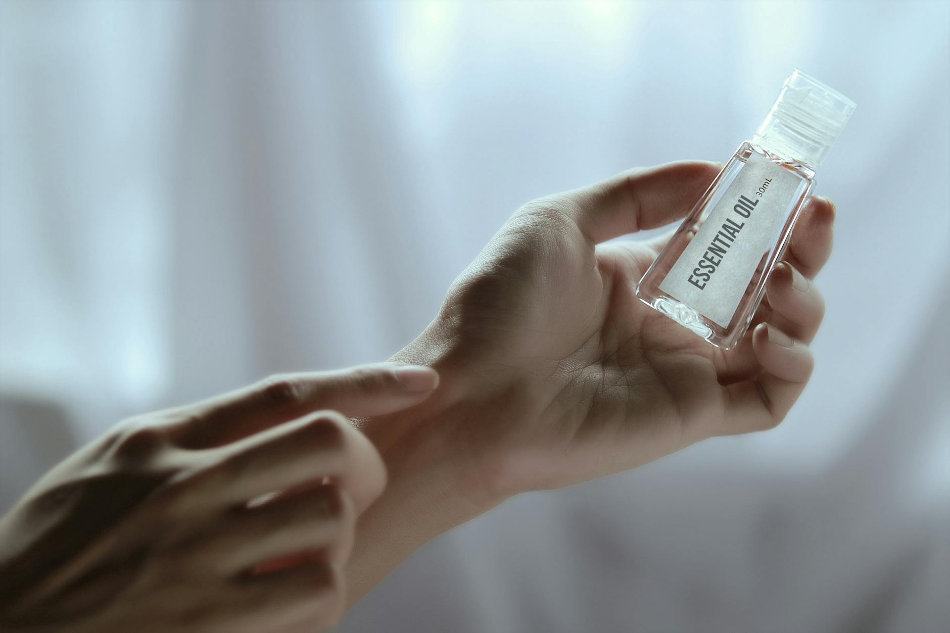 Close-up of a hand holding an essential oil bottle, ideal for wellness and skincare concepts.